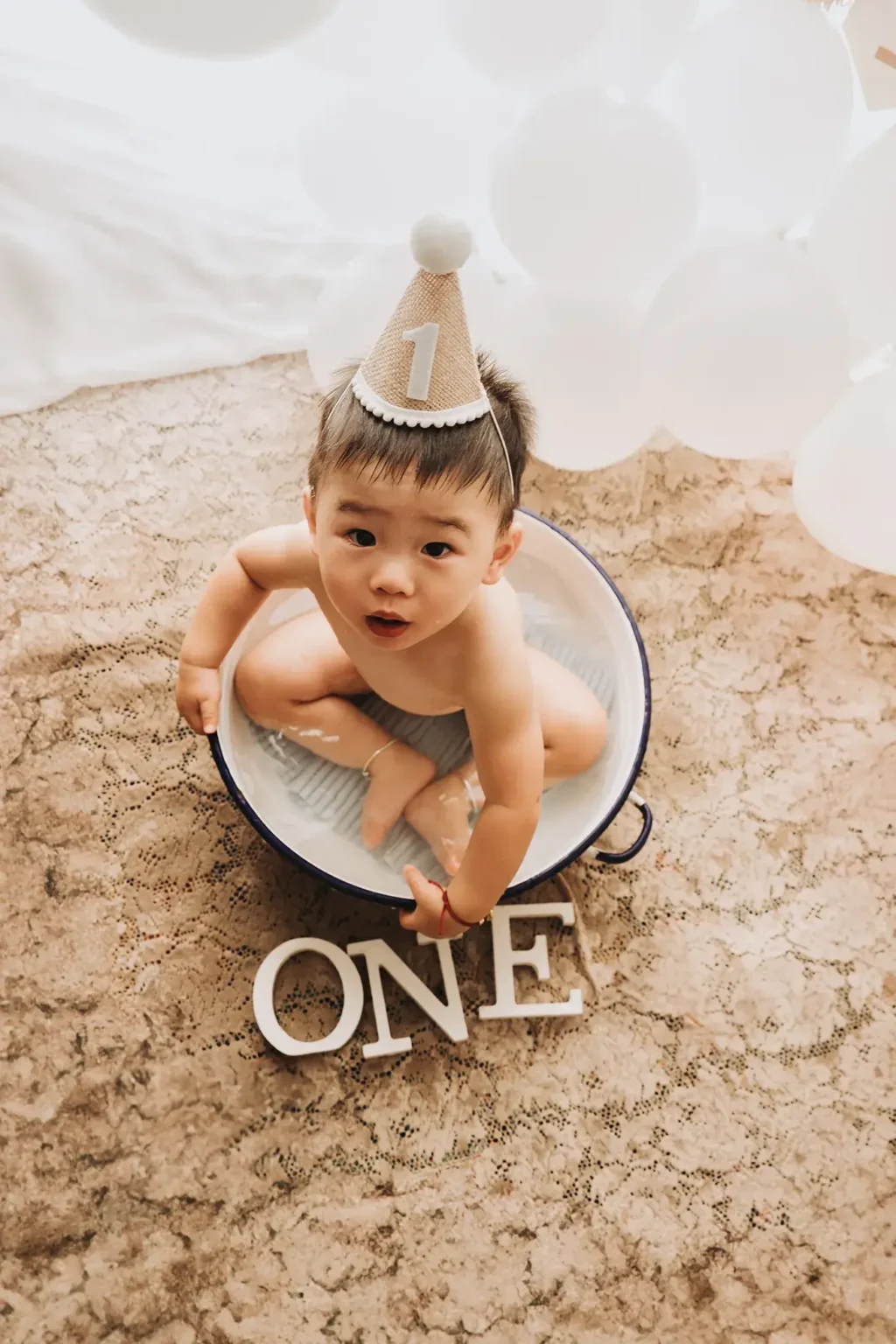 Servizio fotografico smash cake a San Severo (Foggia), bambino nel bagnetto con cappellino per il primo compleanno, set fotografico per bambini in studio professionale in Puglia
