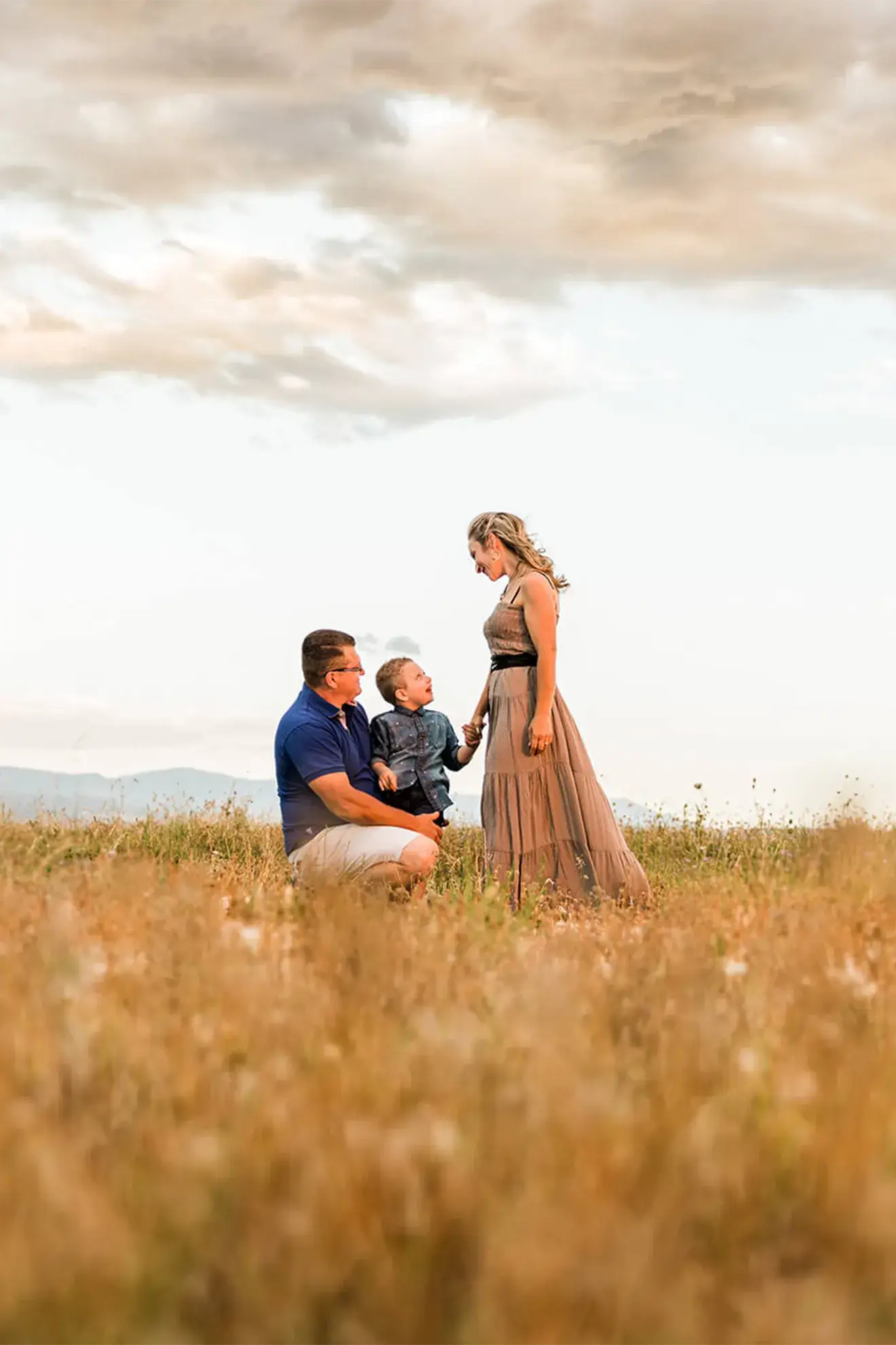 Servizio fotografico di famiglia all’aperto a San Severo (Foggia), genitori e bambino in un campo al tramonto, ritratto familiare naturale e luminoso in Puglia